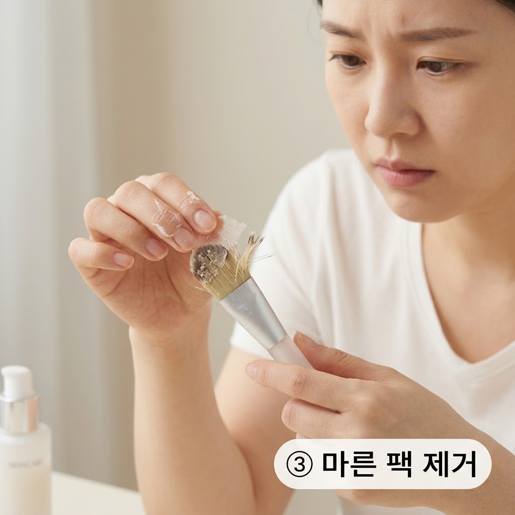 브러쉬 손상을 막기 위해 굳은 팩을 억지로 뜯어내는 행동을 멈추고 두 손으로 사용 직후의 브러쉬를 흐르는 물로 가져가 세척을 준비하는 모습.